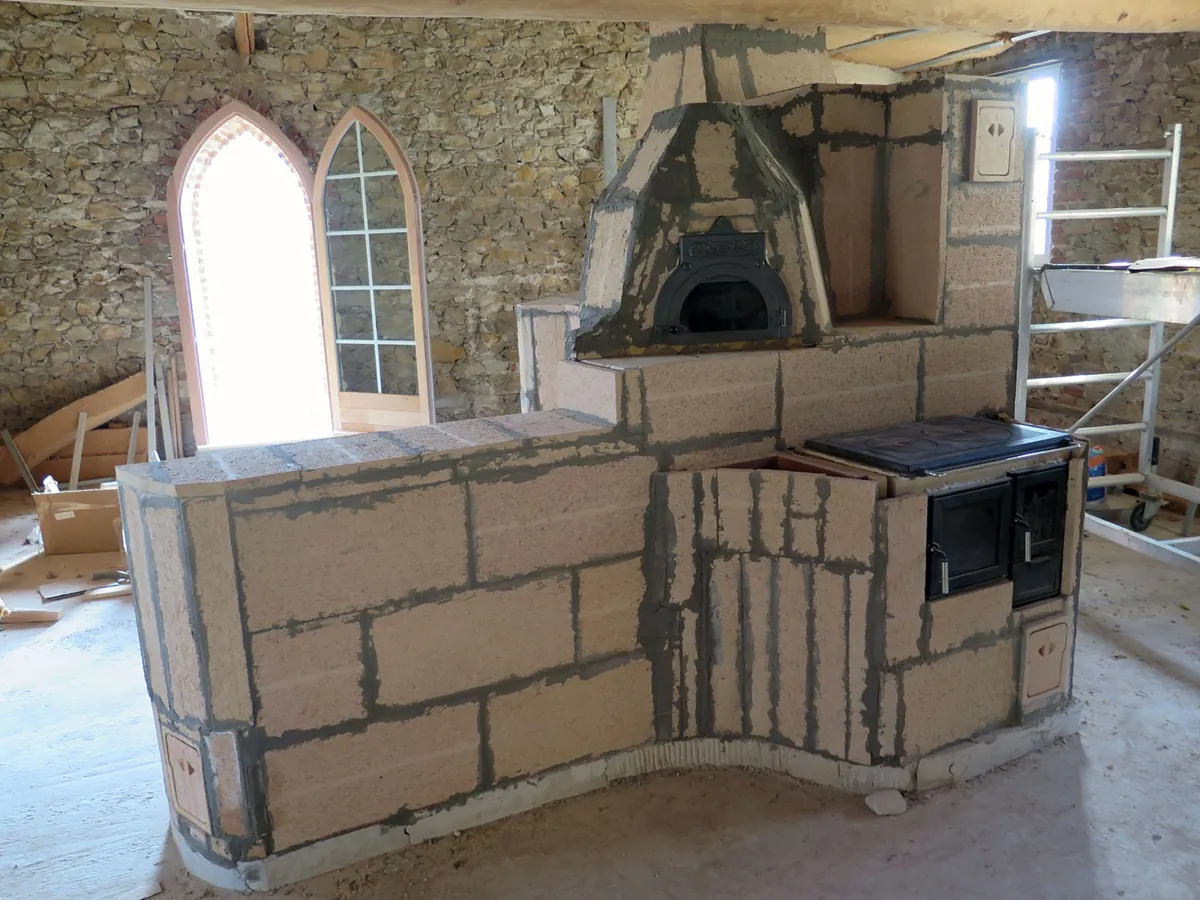 Horno de pan con puerta abovedada, construido en ladrillo encima de una cocina de fundición integrada en una estufa de masa