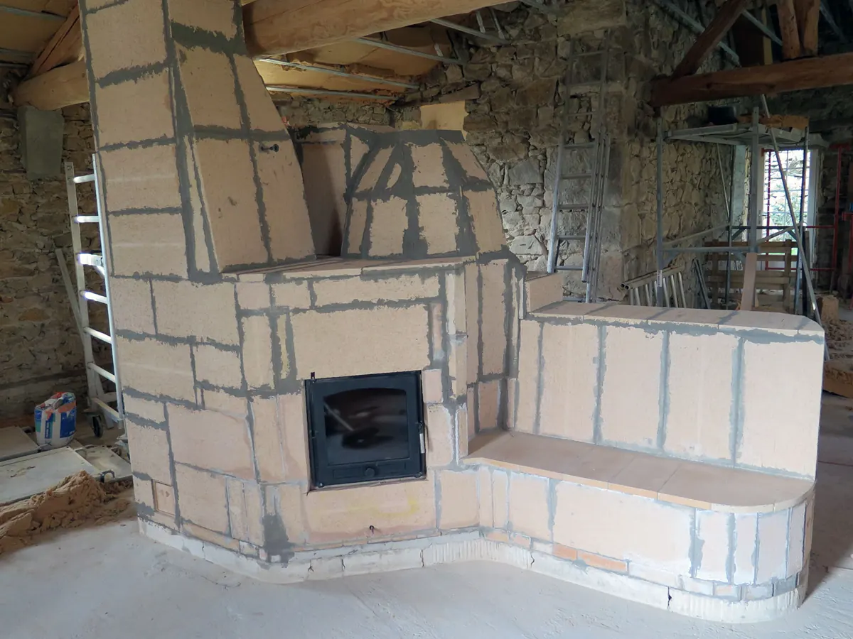 Estufa de masa terminada de ladrillos refractarios, con un hogar de puerta acristalada y un banco calefactado